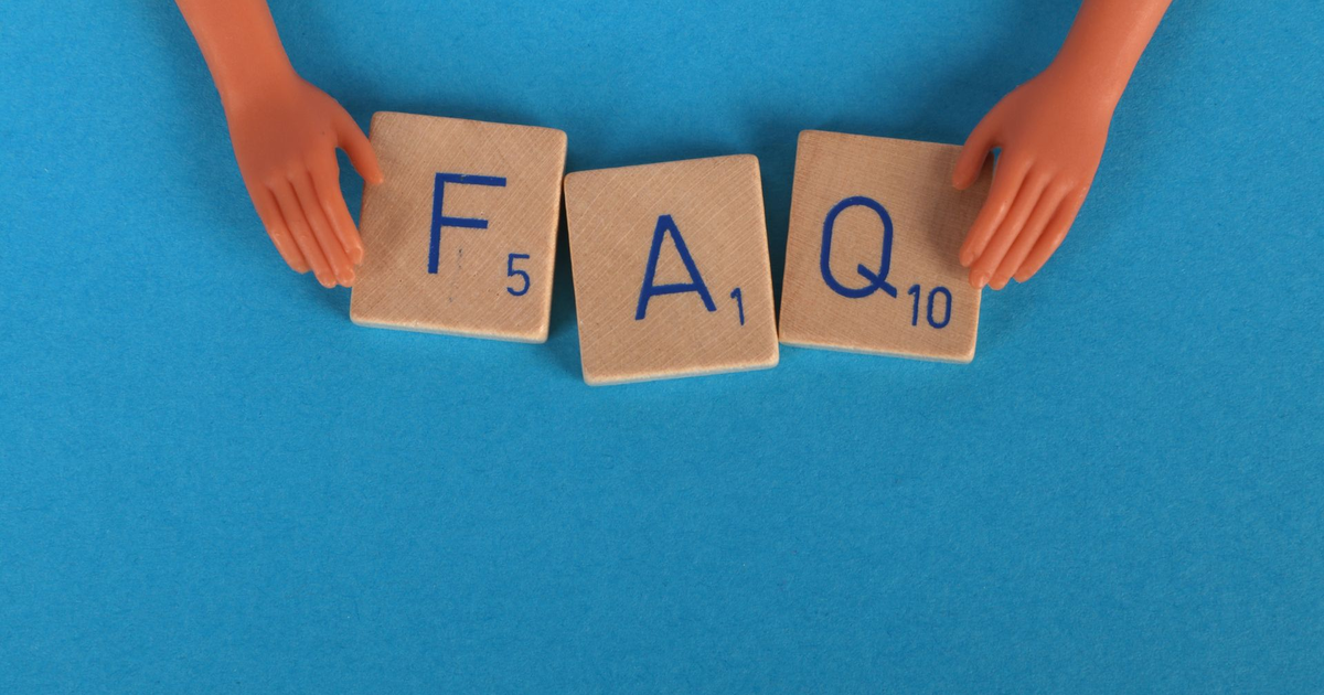Letter tiles spelling FAQ held by two small toy hands on a blue background.