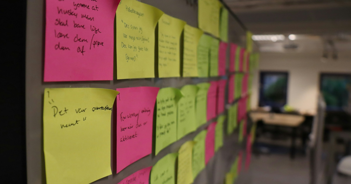 Pink and yellow sticky notes covering an office wall.