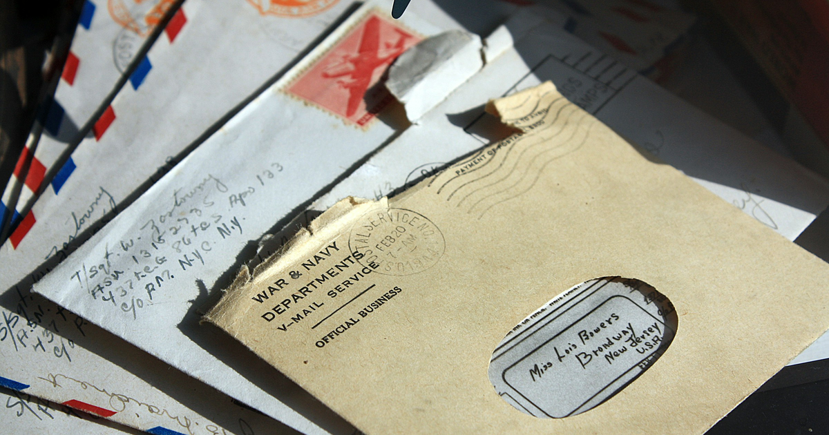 Stack of opened envelopes and windowed mail on a table.