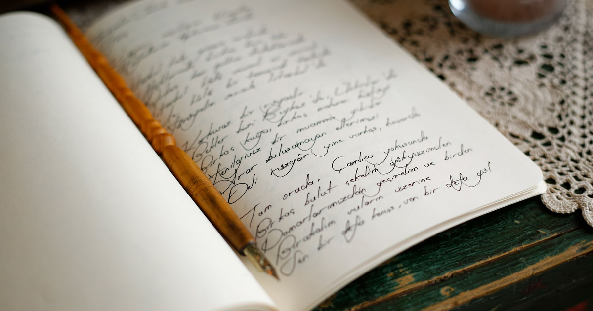 Open journal filled with handwritten notes beside a wooden pen.